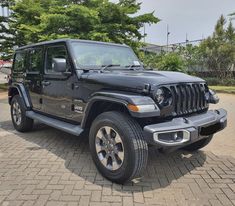 a black jeep is parked in front of some trees