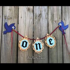 two blue birds are hanging from a string with the word one on it and another bird is