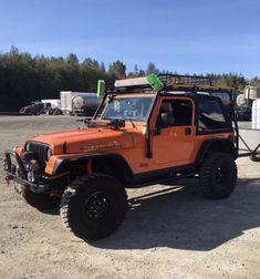 an orange jeep is parked in the dirt