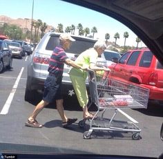 an older man pushing a shopping cart in a parking lot next to another old man