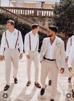 a group of men standing next to each other wearing white suits and ties with brown suspenders