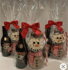 three wine bottles wrapped in clear plastic and decorated with snowmen, candy canes and bows