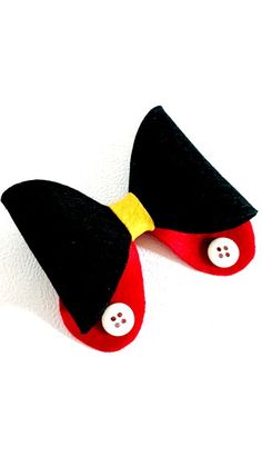 a pair of black and red slippers with buttons on them sitting on top of a white surface