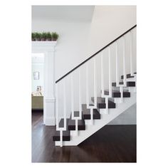 a white staircase with black handrails and wood flooring