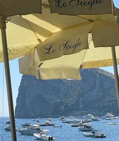 several boats are in the water near some umbrellas with writing on them that read, la toggia