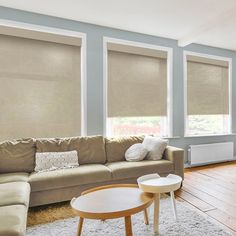 a living room filled with furniture and windows covered in roller shades on top of them