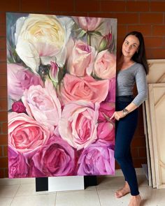 a woman standing next to a large painting of pink and white roses on a canvas