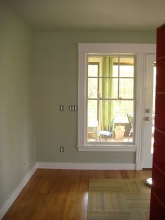 an empty room with a window and hard wood flooring on either side of the door