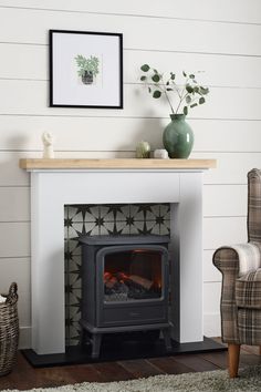 a white fireplace with a wood burning stove in the center and a chair next to it