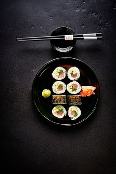 a black plate topped with sushi and chopsticks