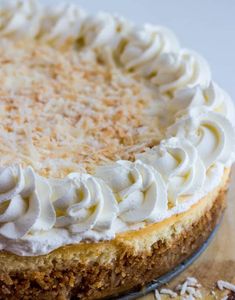 a cake with white frosting and coconut flakes on top is sitting on a table