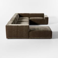 a large brown couch sitting on top of a white floor next to a footstool