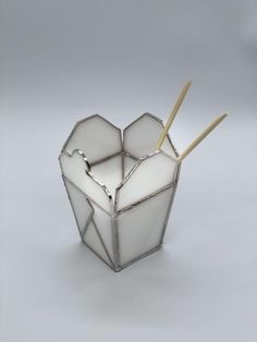 a glass container with chopsticks in it on a white surface and gray background