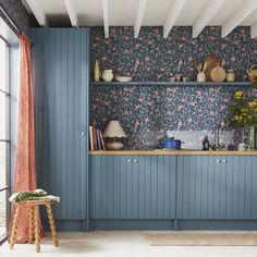 a kitchen with blue cabinets and floral wallpaper