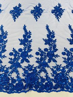 blue lace with flowers and leaves on white fabric, close - up view from above