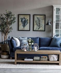 a living room with blue couches and two pictures on the wall above each sofa