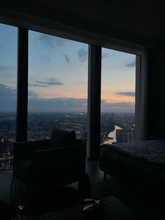 a bedroom with large windows and a view of the city at sunset or dawn from it