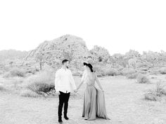 black and white photo of a couple holding hands while standing in the middle of desert