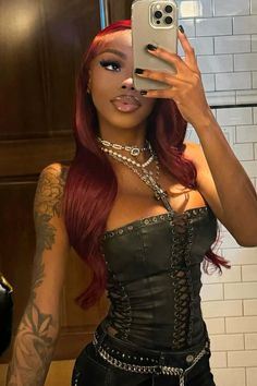 a woman with red hair taking a selfie in a mirror wearing a corset