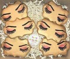 four decorated cookies in a box with eyelashes