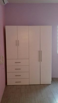 an empty room with white cabinets and pink walls