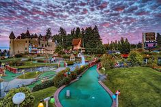 a miniature golf course in the middle of a small town at sunset or dawn with colorful clouds