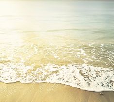 an ocean beach with waves coming in to the shore and sun shining on the water