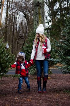 a woman and child walking through a christmas tree lot