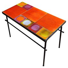 an orange table with multicolored tiles on it's top and black metal legs