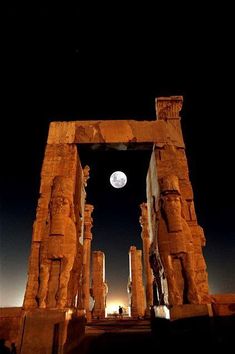 the full moon is setting over some ancient ruins