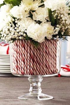 a christmas centerpiece with white flowers and red and white candy canes in it