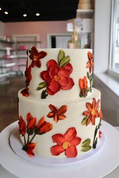 a three layer white cake with red flowers on it