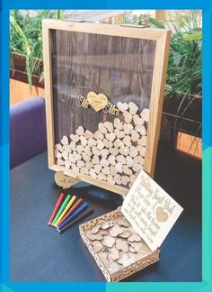 a wooden box filled with lots of wood chips next to a card board and markers