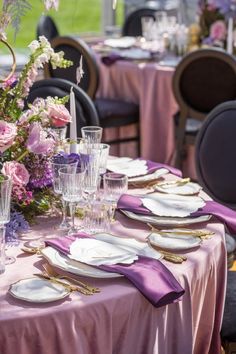 the table is set with plates, silverware and purple napkins for an elegant dinner