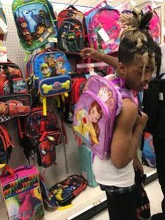 two children are looking at backpacks in a store