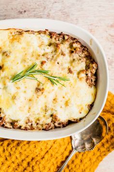 a casserole dish with meat and cheese in it on a yellow place mat