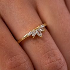 a woman's hand wearing a gold ring with three leaves on it and two diamonds in the middle