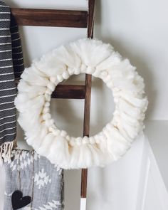 a white wreath sitting on top of a wooden ladder