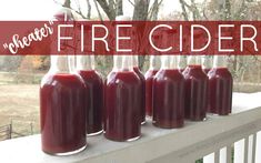 six bottles filled with red liquid sitting on top of a porch