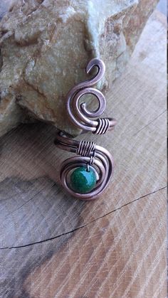 a piece of jewelry sitting on top of a wooden table next to some rocks and a rock