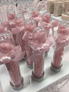 there are many pink candies in vases with bows on the top and ribbons around them