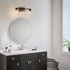 a bathroom with two sinks and a round mirror