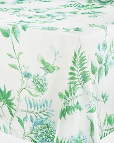 a white table cloth with green leaves and flowers on it