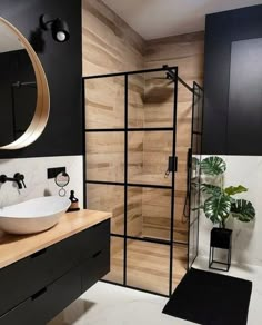 a bathroom with black and white walls, wooden flooring and a glass shower stall