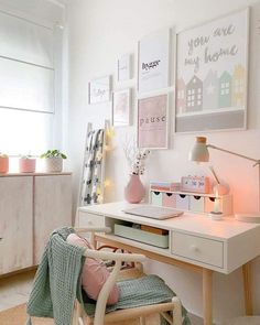 a white desk and chair in a room with pictures on the wall above it,