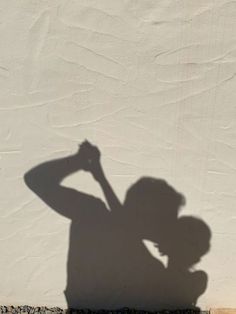 a shadow of a person holding a skateboard in front of a white wall,