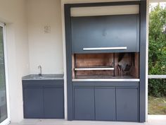 an outdoor kitchen with built in grill and cabinets on the outside wall, next to a sliding glass door