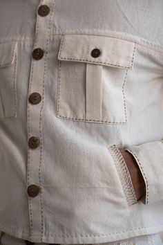 This Dawning Shirt Jacket comes in a calm and soothing color. This 30s cotton shirt jacket is undyed and unbleached. This full-sleeve shirt jacket comes with statement buttons, panelling and side pockets. Stitches of Kantha, a form of Indian hand embroidery, line the pockets and panels. *This item is a final sale and not eligible for returns or exchanges. *This item can take up to 14 business days to ship as it is made to order for you. Indian Hand Embroidery, Slow Clothing, Embroidery Men, Wrap Top Blouse, Womens Wrap Dress, Men's Ethnic Wear, Outfits Woman, Sustainable Clothing Brands, White Denim Jacket