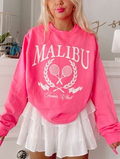 The Sassy Shortcake Pink Malibu Club Crewneck is a hot pink preppy sweatshirt. She features twin tennis rackets and the text "Malibu Tennis Club" in white. She is soft, lightweight, and absolutely adorable! She is paired here with our white pinkalicious skirt. This crewneck is also available in white. Oversized fit + unisex sizing. Model is wearing a size small. Pink Athleisure Sweatshirt For Leisure, Pink Crew Neck Sweatshirt For Leisure, Pink Crew Neck Sweatshirt For Sports, Pink Sweatshirt For College In Spring, Pink Spring College Sweatshirt, Pink Spring Sweatshirt For College, Pink Sports Sweatshirt With Graphic Print, Long Sleeve Graphic Print Sweatshirt For Tennis, Graphic Print Long Sleeve Sweatshirt For Tennis