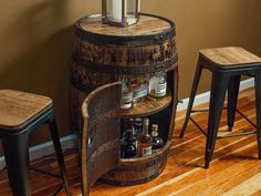 an old barrel is turned into a bar with stools and bottles in it on the floor